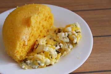 Brazilian couscous and scrambled eggs (Cuscuz com ovo) on wooden background. Typical Couscous of Northeast of Brazil.