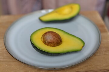 Two halves of a ripe avocado on a platter. Half an avocado with pits. 