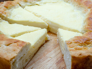 Close-up of triangular slices of sour cream pie - a national Tatar dish. A huge homemade cheesecake with toasted edges and tender filling on a wooden table.