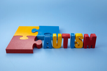 Autism awareness concept with puzzle and word autism on blue background.