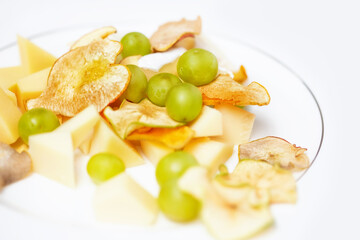 Cheese plate for breakfast with slices of various cheeses, dried apple wedges
