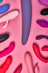 many multi-colored dildos on pink background. image is suitable for sex shop advertising. flat lay. intimate equipment for getting pleasure, private life
