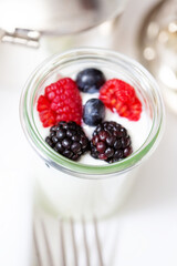 Transparent glass with white farm yogurt and fresh blackberries and strawberries