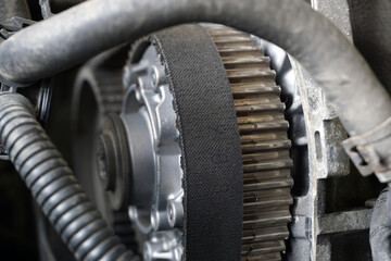 The toothed belt is worn on the toothed wheel. Timing of a modern engine. Selected focus. The background is blurred.
