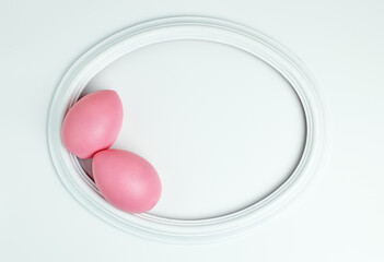 Easter pink eggs in a white oval frame with space for text. Flat lay image composition, top view