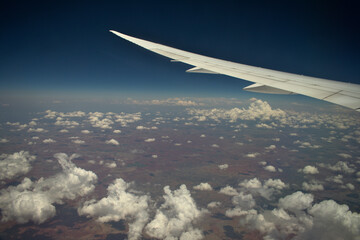Fototapeta premium Wing of an airplane, flying above the clouds