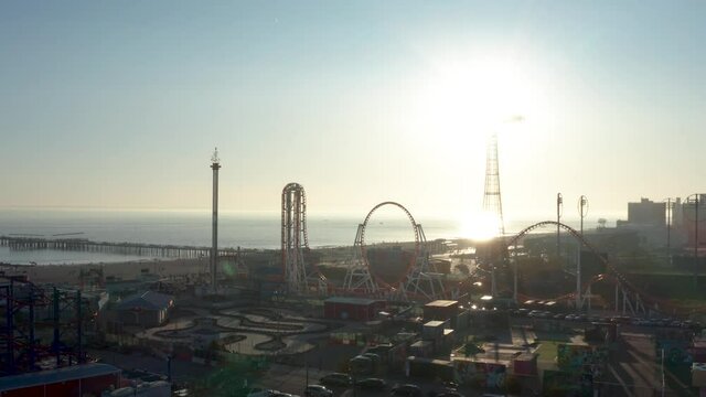 Aerial shot of Coney Island panning/orbiting amusement park rides just before sunset.