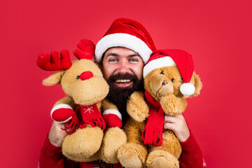 happy bearded man in santa claus hat and knitted sweater with toy celebrate new year winter holiday, christmas present