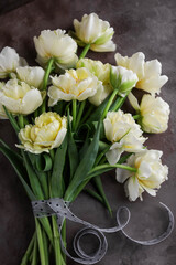 Bouquet of yellow tulips tied with a ribbon. Beautiful delicate flowers on a dark table.