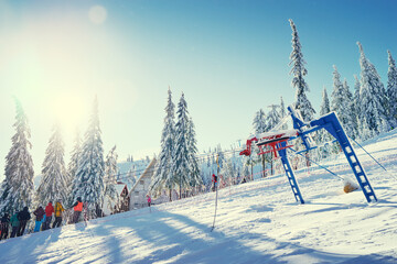 Snowy mountains and ski lifts. Skiers and snowboarders skiing downhill to village.