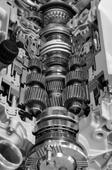 Gear box cross section, engine industry, sprockets, cogwheels and bearings of automotive transmission for oversize trucks and construction vehicles, selective focus, monochrome shot 