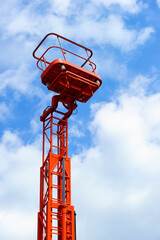 Hydraulic lift platform with bucket of orange construction vehicle, heavy industry, blue sky and white clouds on background  - 417717088
