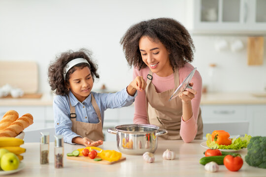 African American Mom Teaching Daughter How To Prepare Soup