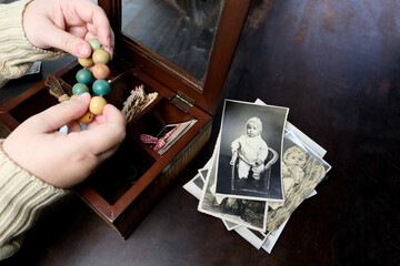 female hands are sorting dear to heart memorabilia in an old wooden box, a stack of retro photos, a...