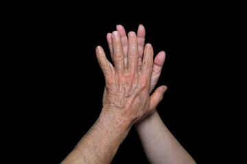 Fototapeta premium male and female hands together on black background, old skin with wrinkles and veins, concept of health, age-related changes, love, tender relationship of a couple in love, isolated image