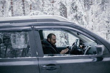 Fototapeta na wymiar man follows the road in a navigator and drives a car through a winter forest