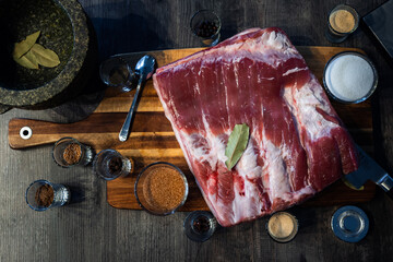 Close up of pork belly with spices, on a wooden board.