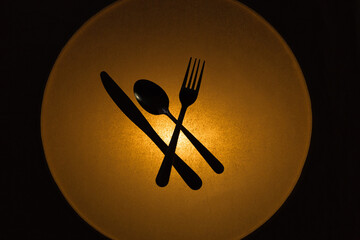 kitchen  cutlery silhouetted by a  golden circular glowing light.