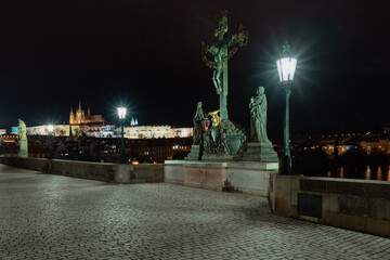 Fototapeta na wymiar view of statues on Charles Bridge originally from the 17th century and light from lanterns and in the background Prague Castle and St. Vitus Cathedral in the center of Prague at night