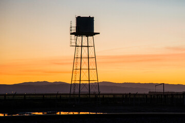 USA, California. San Joaquin River Basin, water tower against sunset.