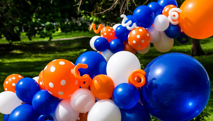 Multicolored balloons float in a park on a sunlit day. 