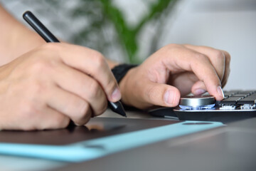 Graphic designer working with digital control wheel and graphic tablet.