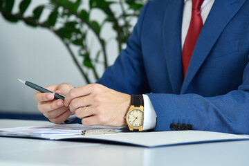 Trader man in suit sitting in office and analyzing report.
