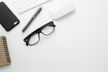 Office workplace with keyboard, notepad, glasses telephone and pen on white background