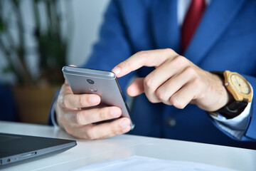 Businessman writes message on smart phone.