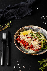 meat with vegetables in a plate on a black textured background