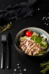 meat with vegetables in a plate on a black textured background