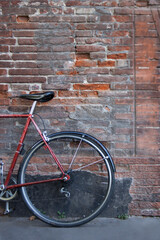 Fototapeta na wymiar Abandoned bicycle leaning on the outside red brick wall. Bike tires. No people around.