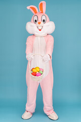 Easter bunny or rabbit or hare with basket of colored eggs, having fun, dancing, celebrates Happy...