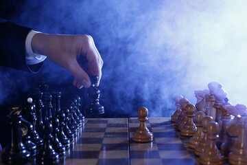 Hand of businessman moving wood chess pieces in a success game competition. Strategy, management or leadership concept