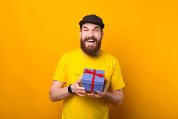 Portrait of joyful man wearing yellow t shirt and holding a gift.