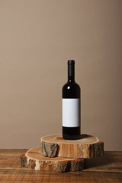 Blank white label mock up on black bottle of unlabeled red wine on a wooden table. Alcohol bottle mockup presentation ready for logo design. Full drink bottle template with empty sticker.