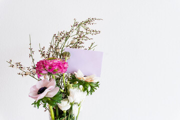 mazzo di fiori colorato e biglietto di auguri rosa su sfondo bianco