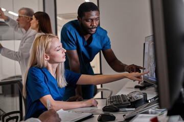 Team of radiologists looking at patient CT scan image at display discussing treatment of patient in x-ray room.Medical planing treatment concept.