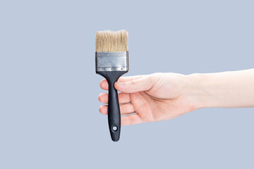 handyman repair minimal concept. worker holding paint brush isolated over gray background