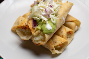 Fried tacos called flautas with guacamole and cabbage on white background. Mexican food