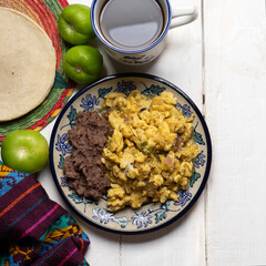Scrambled eggs with green sauce and refried beans on white background. Mexican food