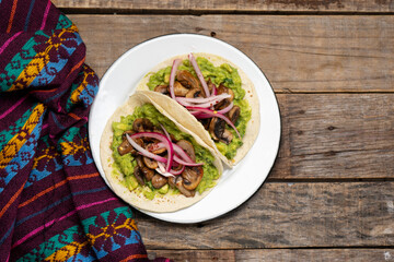 Mushroom and guacamole tacos on wooden background. Mexican food
