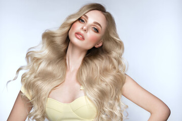 Beautiful blond girl with a perfectly curls hair, and classic make-up. Beauty face and hair.