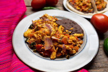 Scrambled eggs and refried beans on wooden background. Mexican food