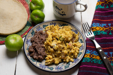 Scrambled eggs with green sauce and refried beans on white background. Mexican food