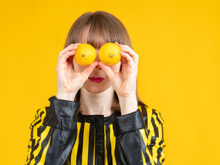 Woman with lemons in her hands. The woman depicts eyes with the help of fruits. Lemon eyes.