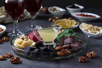 Multicolored gourmet cheese, olives, nuts, honey and sliced lemon on dark background. Appetizer for a wine party