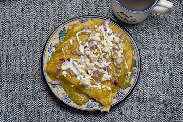 Green enchiladas with fresh cheese and sour cream on blue background. Mexican food