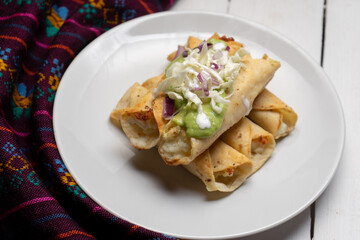 Fried tacos called flautas with guacamole and cabbage on white background. Mexican food