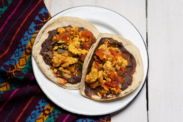 Scrambled eggs and refried beans tacos on white background. Mexican food